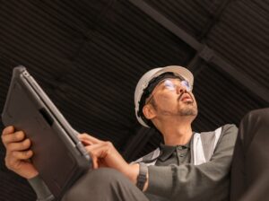A man in a hard hat holding a laptop