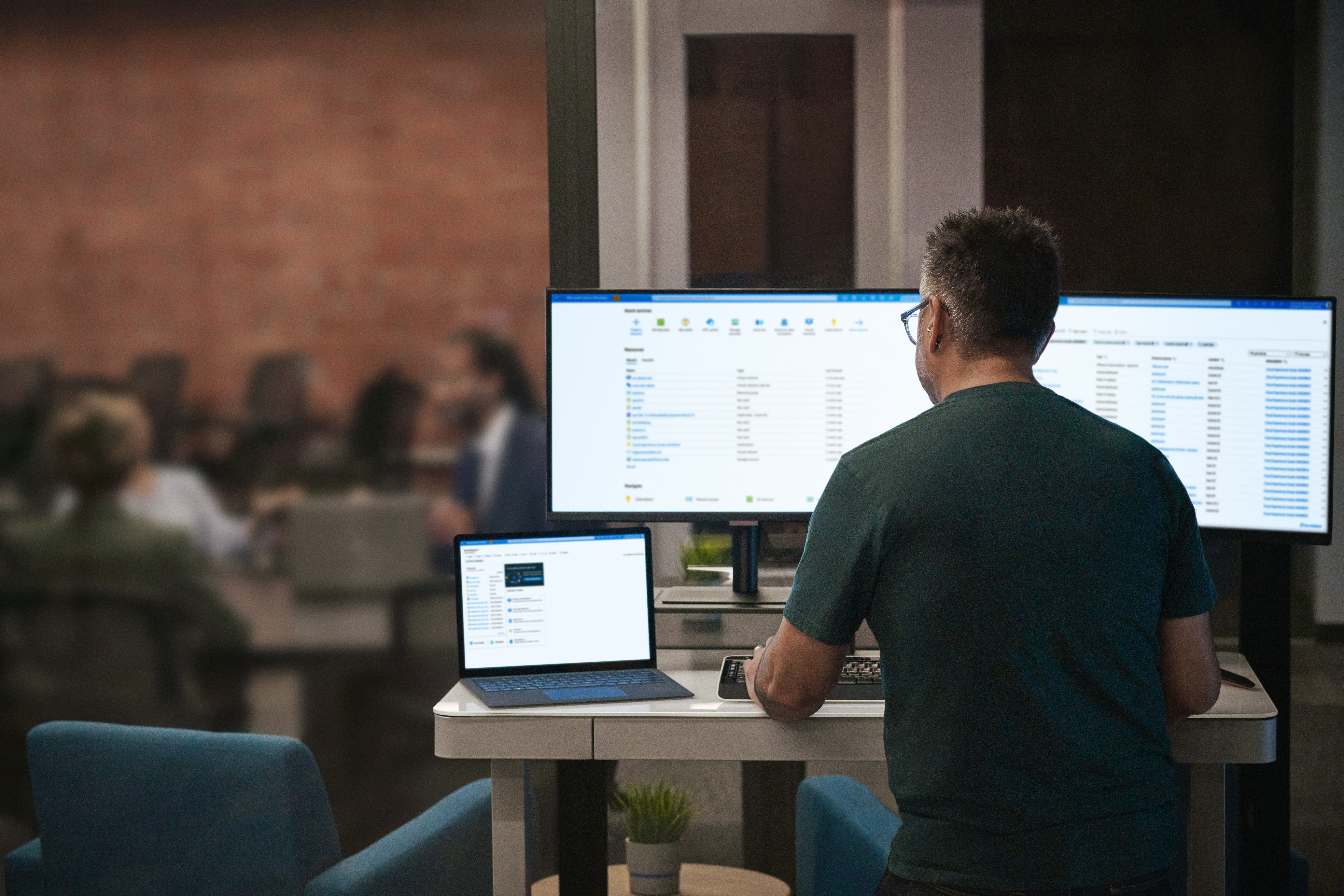 A man sitting at a desk with a laptop and a computer