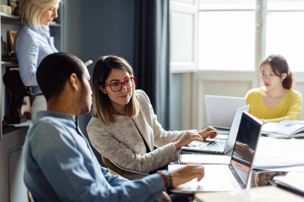 A man and woman collaborating on a laptop in an office